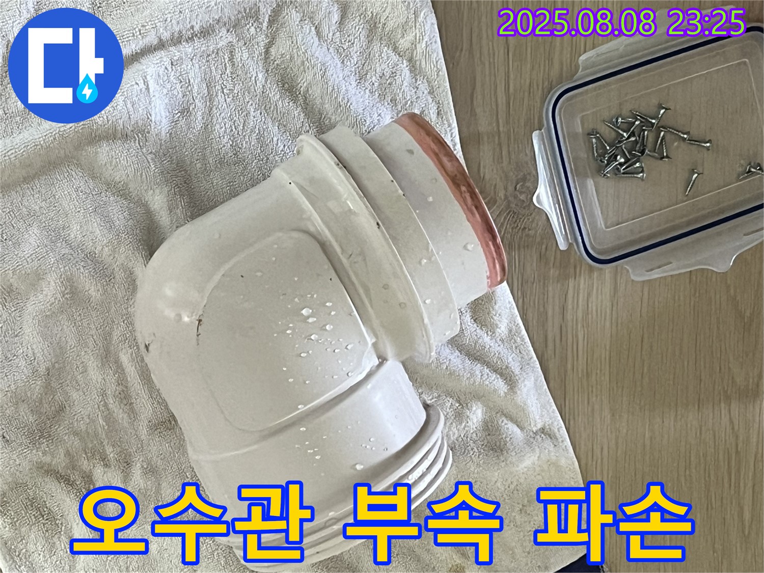 젖은 수건 위의 오수관 부속 - 파손된 오수관 부속을 보여주는 사진입니다.