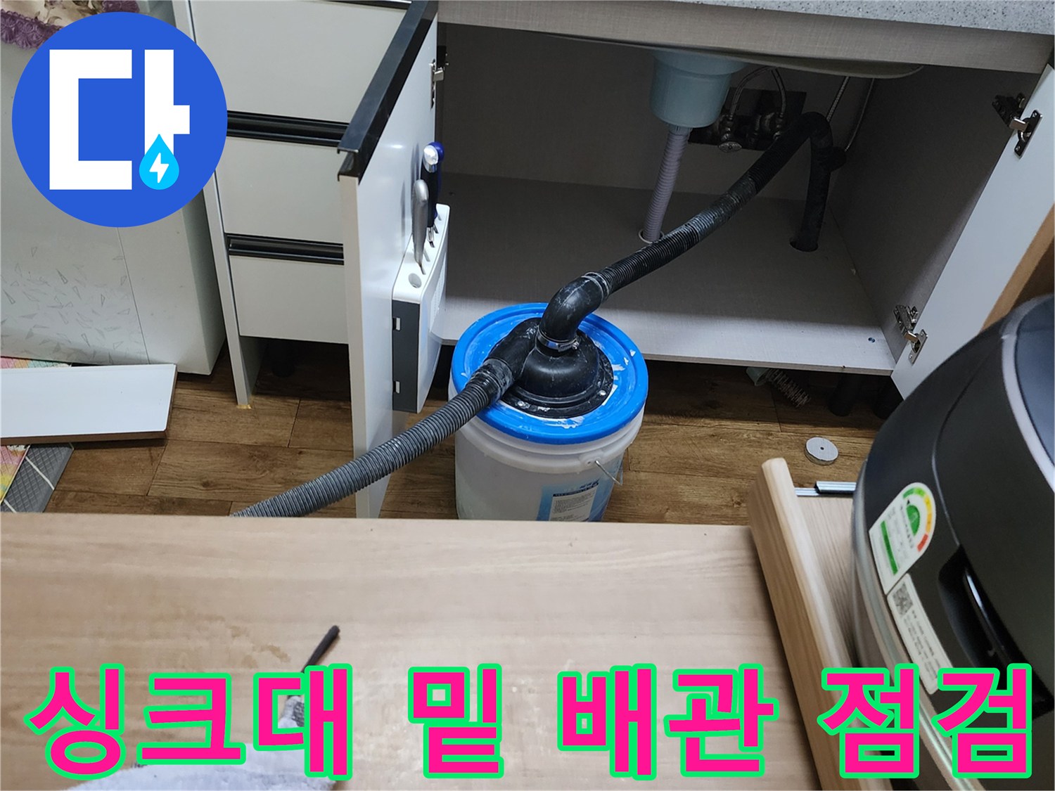 싱크대 하부장 배관 누수를 확인하고 물을 받기 위해 양동이를 놓은 사진