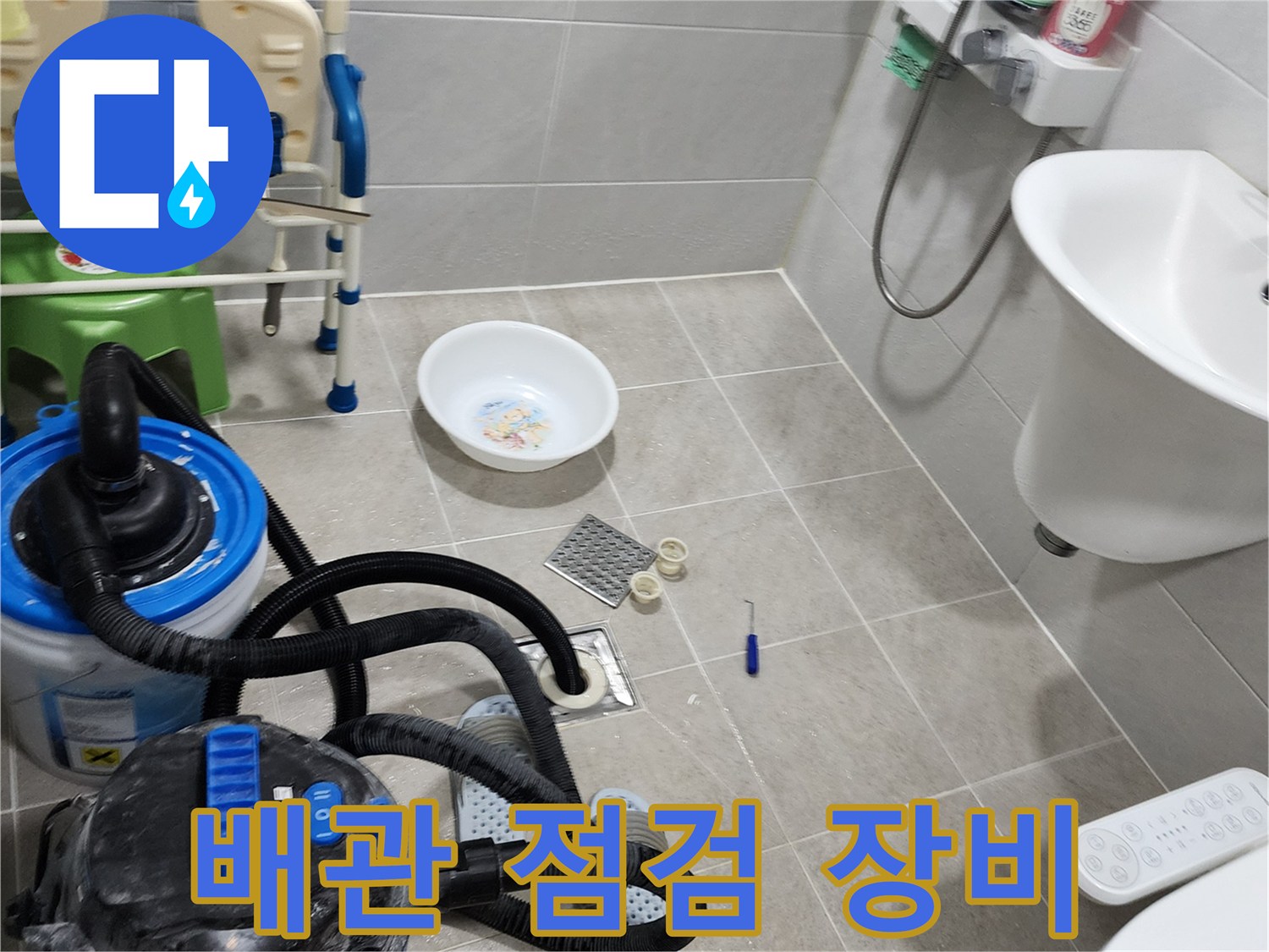 배수구 주변의 누수 지점을 찾기 위해 습식 청소기와 점검 도구를 배치한 모습입니다.