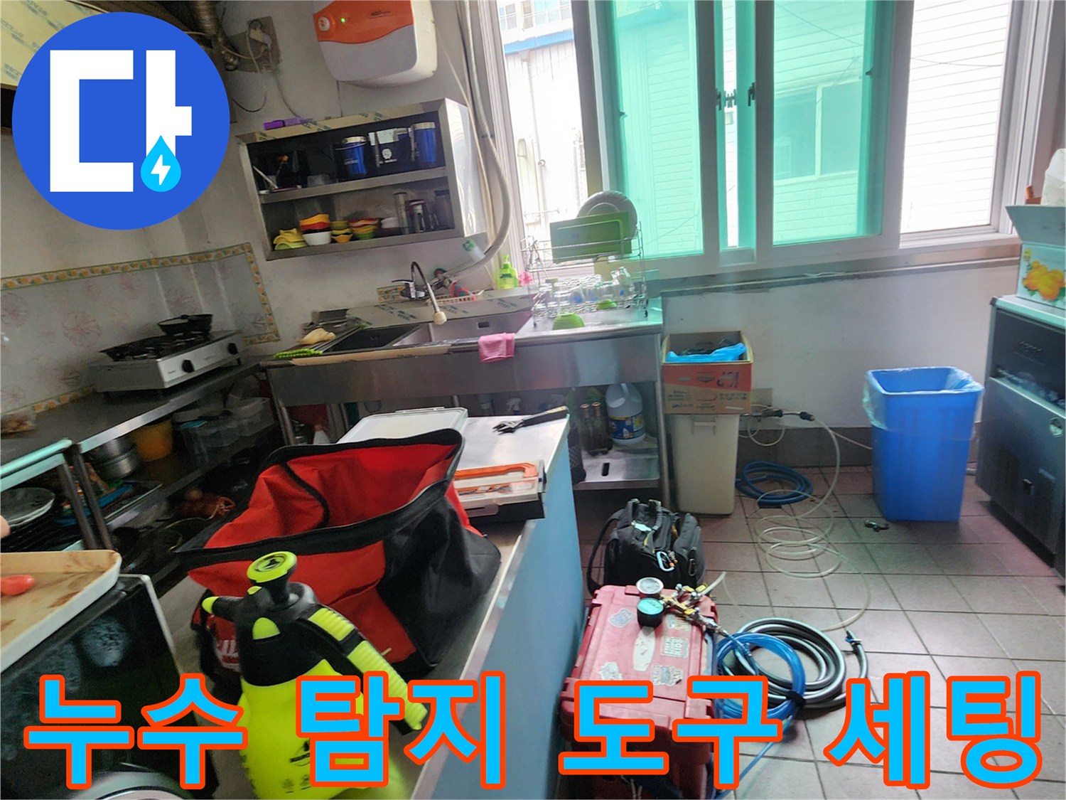 주방 작업대 옆에 놓인 빨간색 공구함과 누수 확인용 가스 탐지기