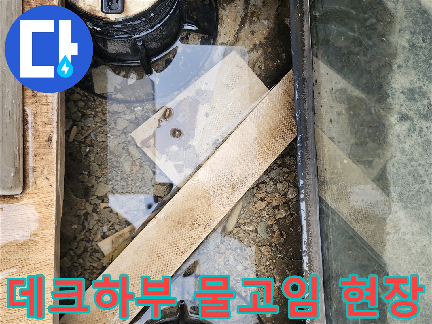 외부 데크 아래쪽 바닥에 물이 고여 있고 배수 캡 주변이 오염된 상태입니다.