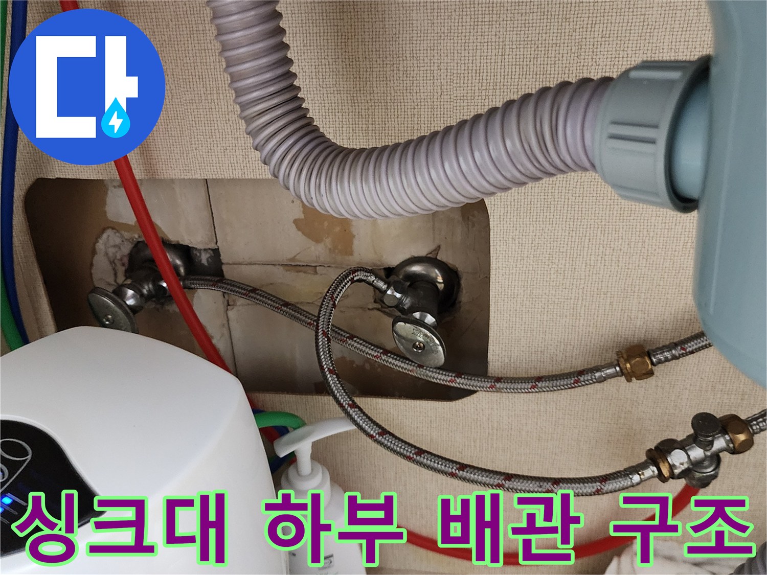 주방 싱크대 아래-회색 주름관과 금속 밸브의 모습