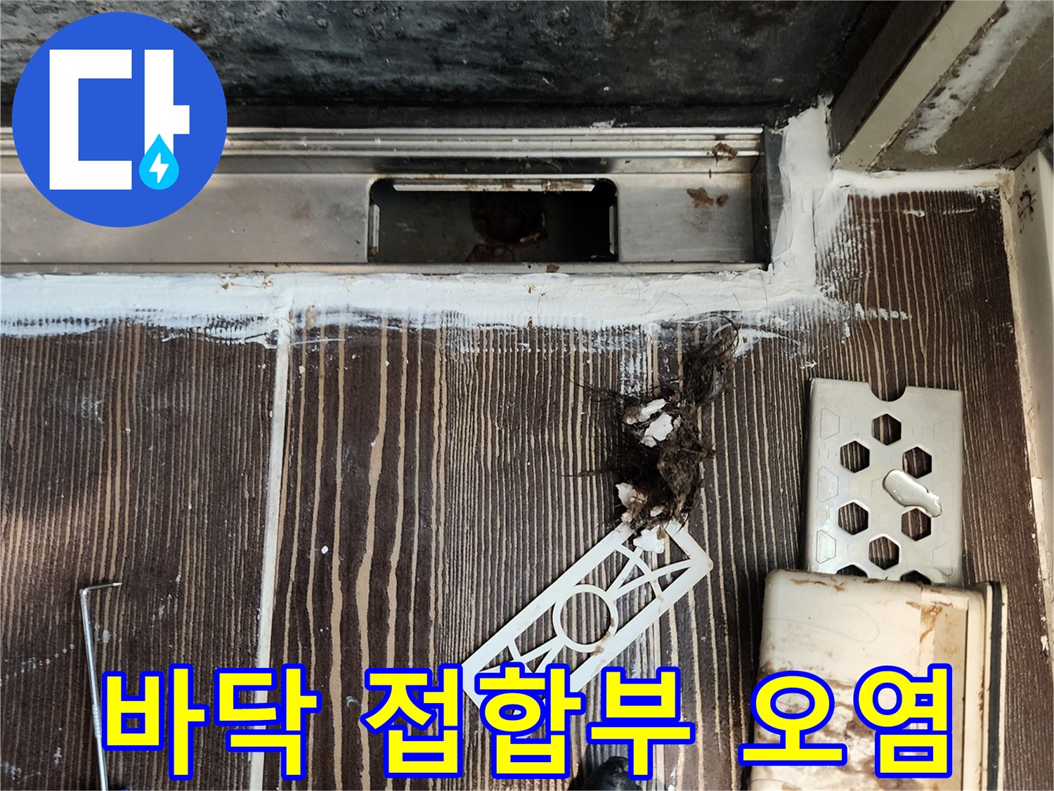 싱크대 하단 배관 주변의 젖은 바닥과 부식된 자재 상태를 보여주는 사진입니다.
