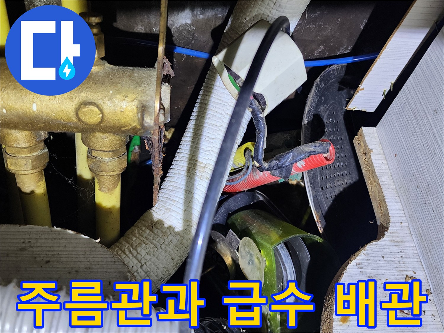 복잡하게 연결된 주방 하부 배수 호스와 금속 급수관의 근접 촬영