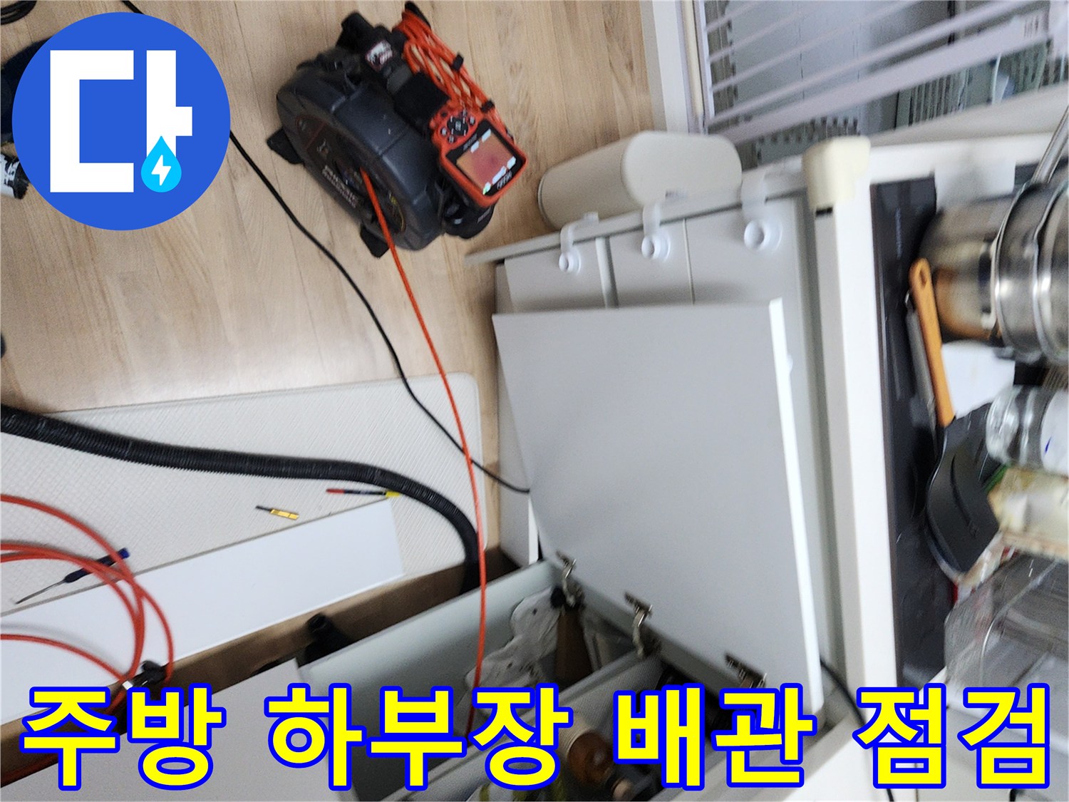 싱크대 하단 공간에 배치된 누수 탐지용 장비와 케이블입니다.