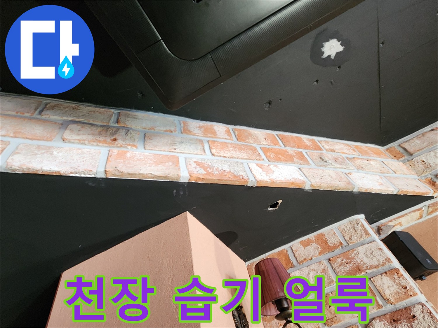 벽돌 벽면 위 검은 천장재의 하얀색 누수 오염 부위