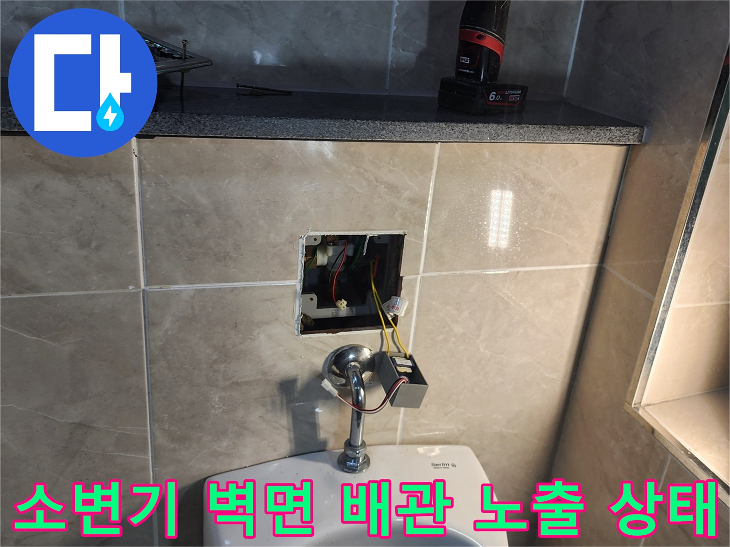 상가 화장실 소변기 뒤쪽 타일을 제거하여 드러난 매립 배관과 전기 부속 상태