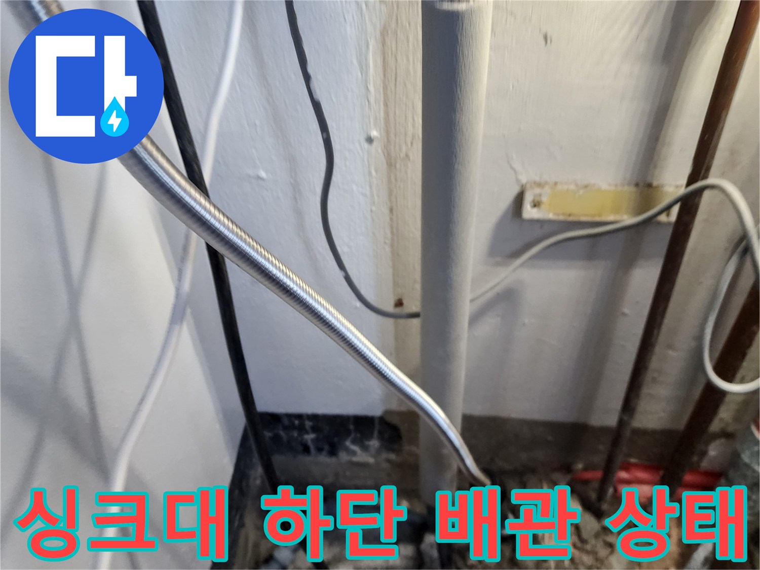 싱크대 아래쪽 배관과 연결된 호스들의 복잡한 모습입니다.
