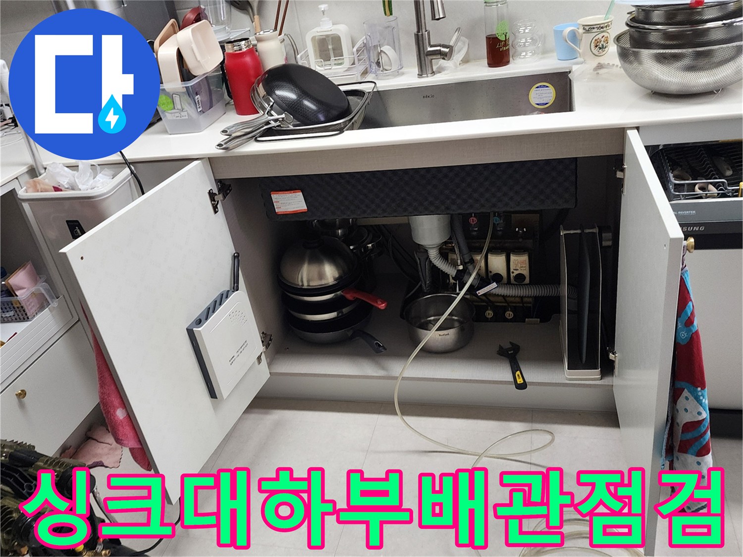 주방 싱크대 하부장 내부의 배관 연결 상태와 점검 장비 모습