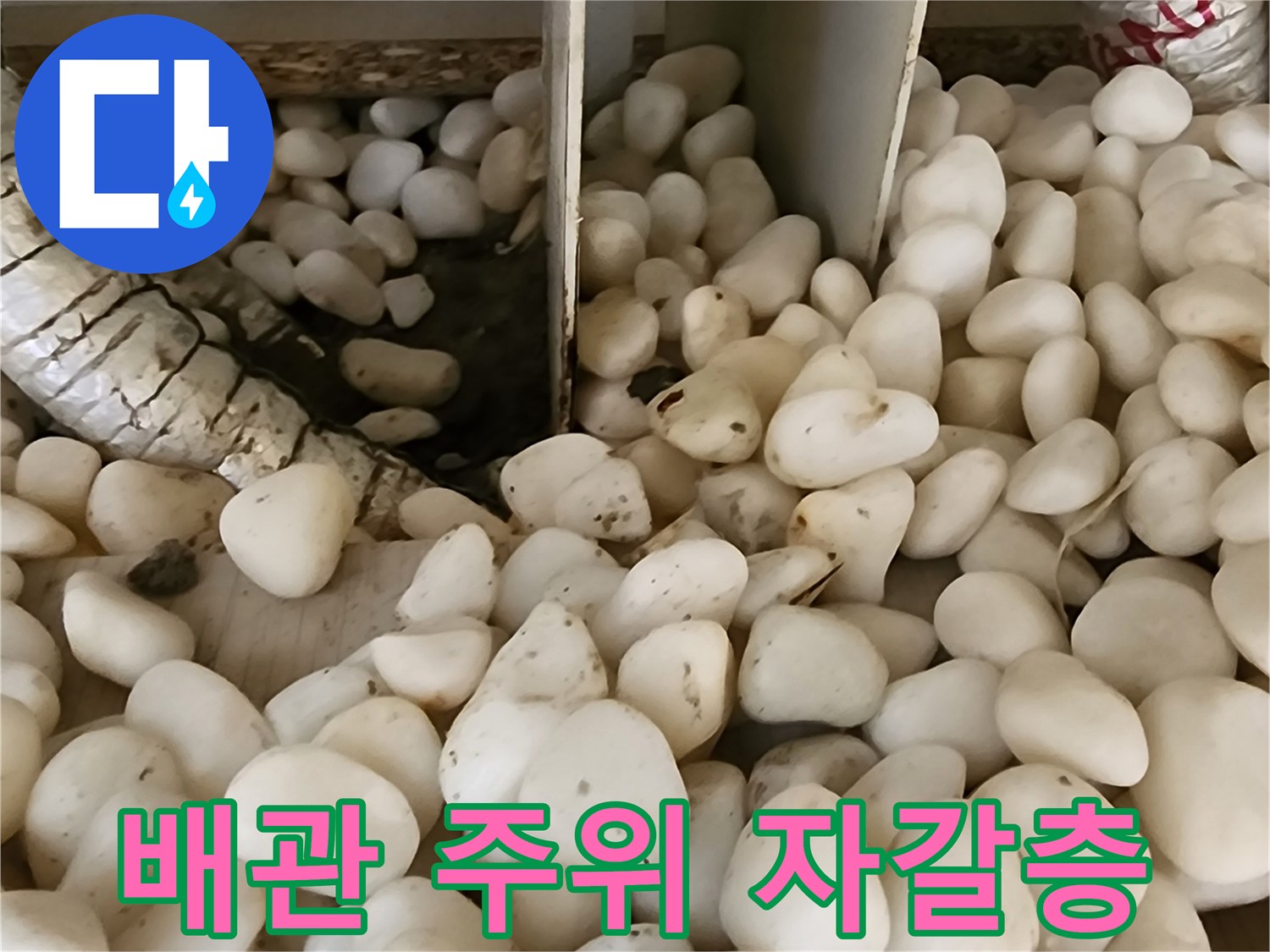 은박 보온재로 감싸진 배관과 주변의 흰색 자갈층 모습입니다.