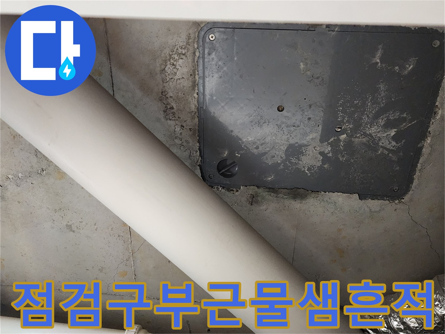 점검구 주변의 젖은 벽면과 배관 연결 부위 사진입니다.