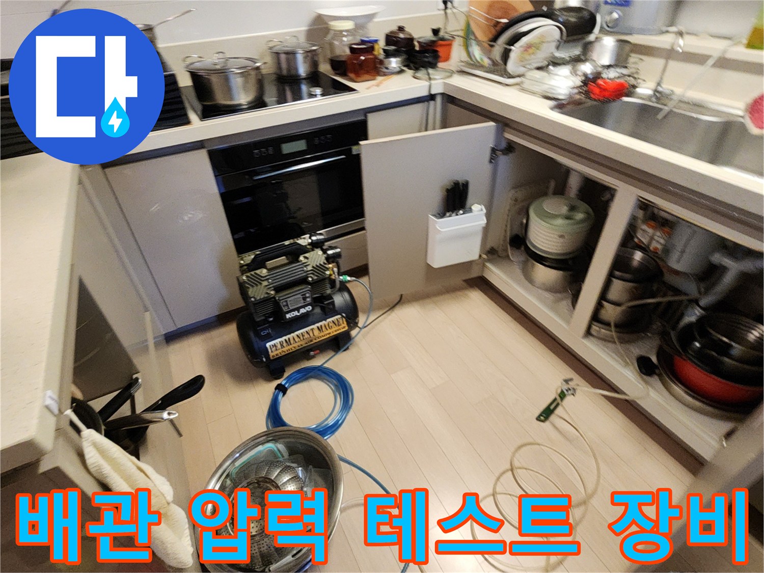 누수 지점 탐지를 위해 주방 바닥에 배치된 공압 측정용 콤프레샤와 호스