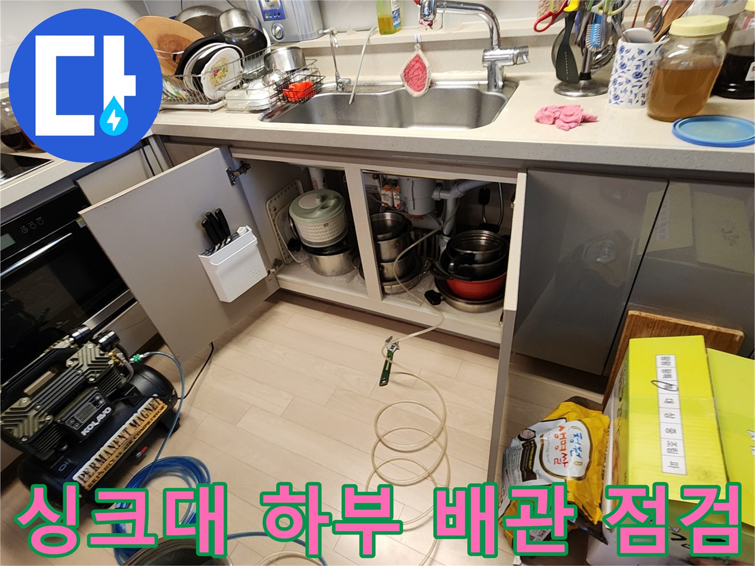 주방 싱크대 아래 배관과 공압 장비가 설치된 현장