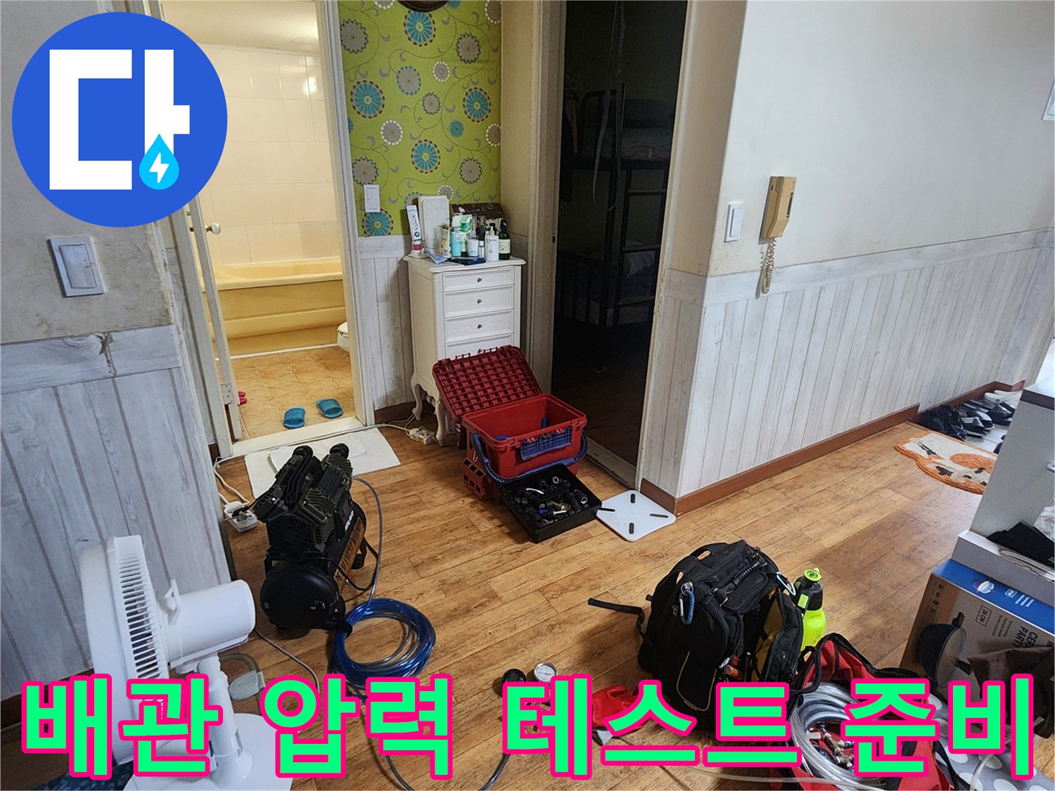 욕실 입구 근처에 놓인 배관 점검용 공기압 측정 장비와 호스