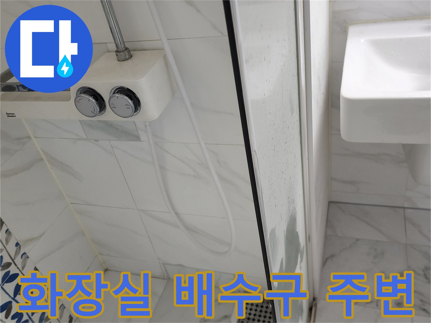 샤워기 수전과 세면대-하단 타일 및 배수구 근접 촬영