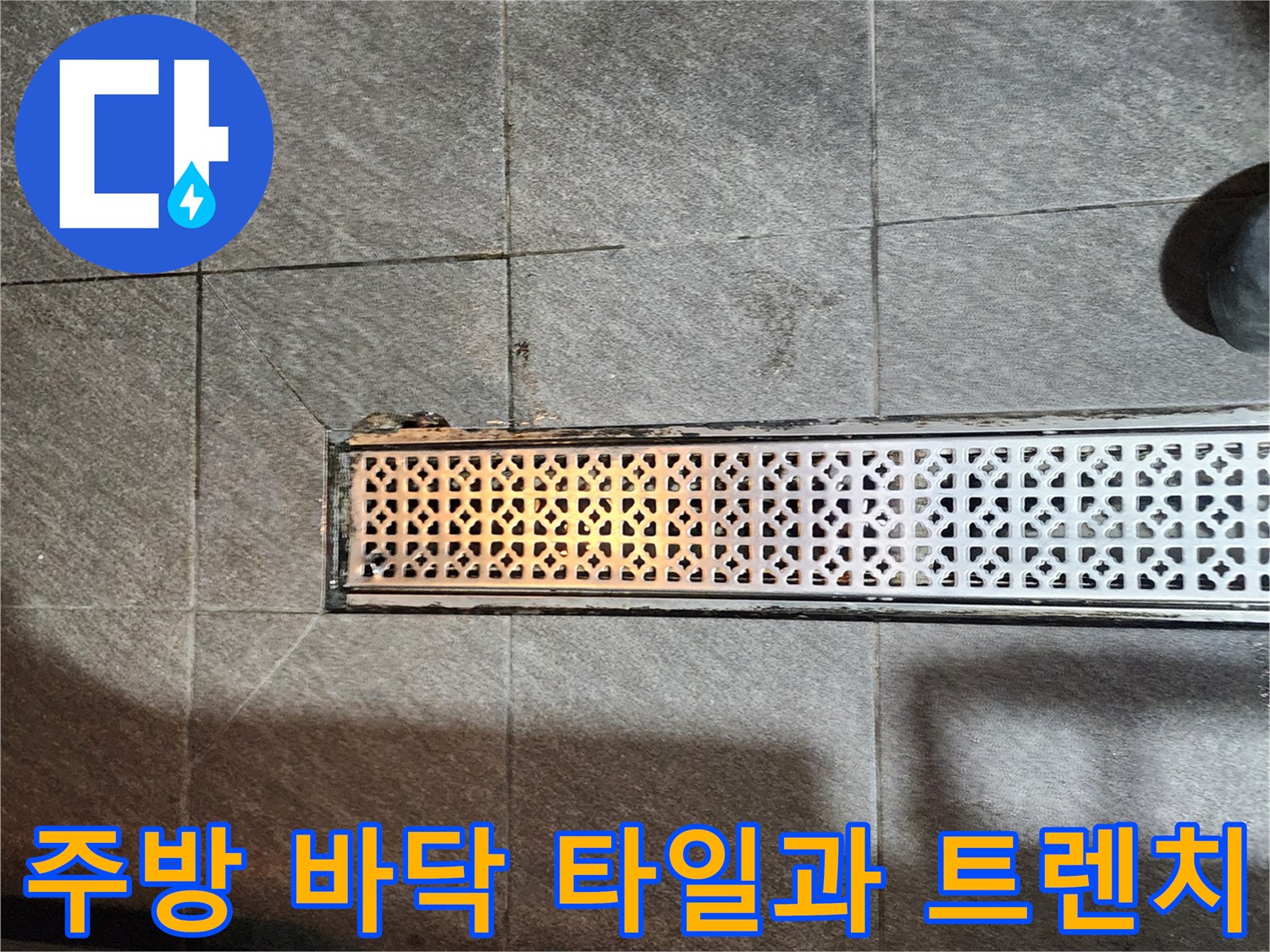 어두운 색상의 바닥 타일과 금속 배수구 트렌치 경계