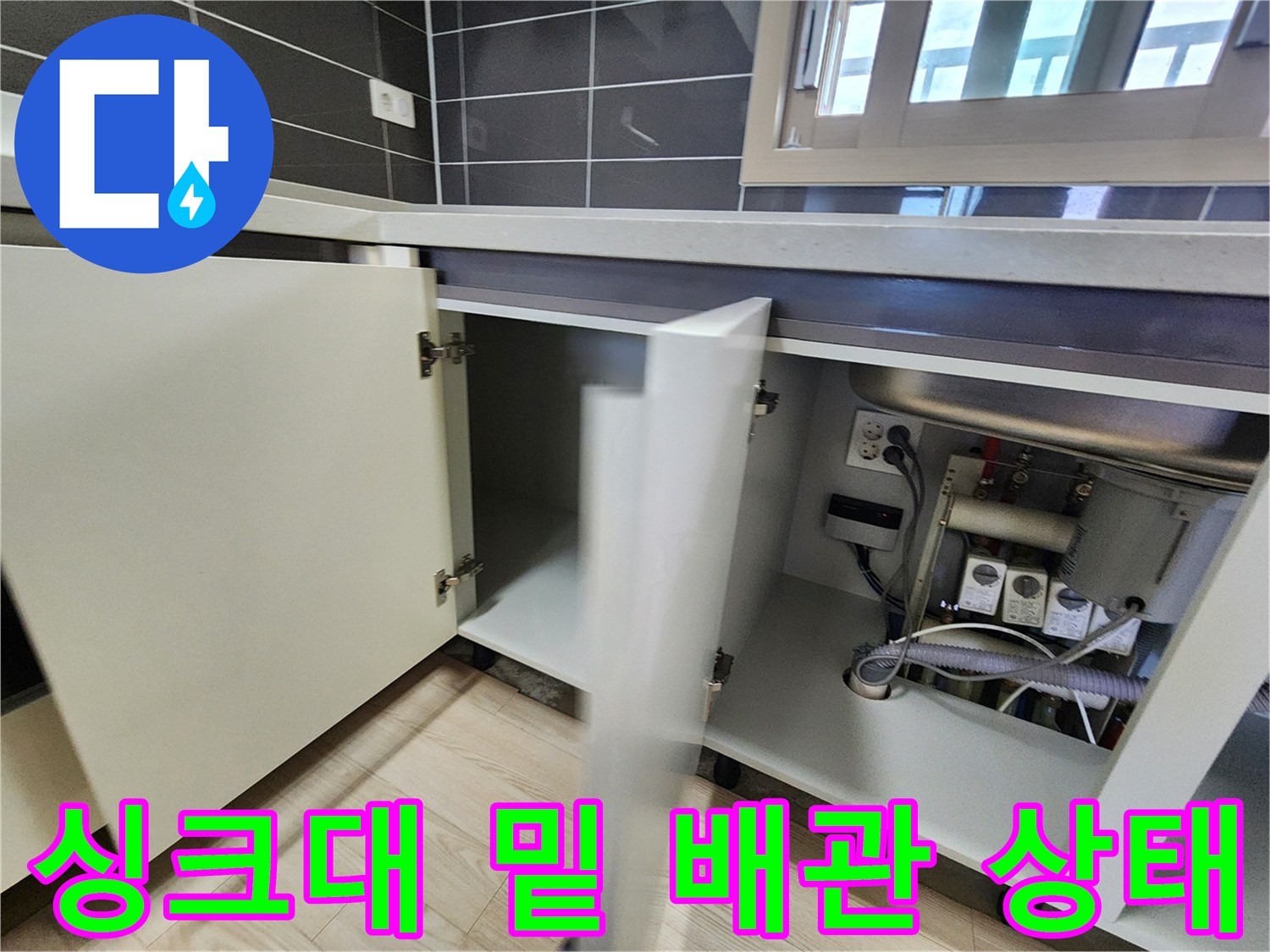 싱기대 하부장 내부-배관과 전기 콘센트가 보이는 모습