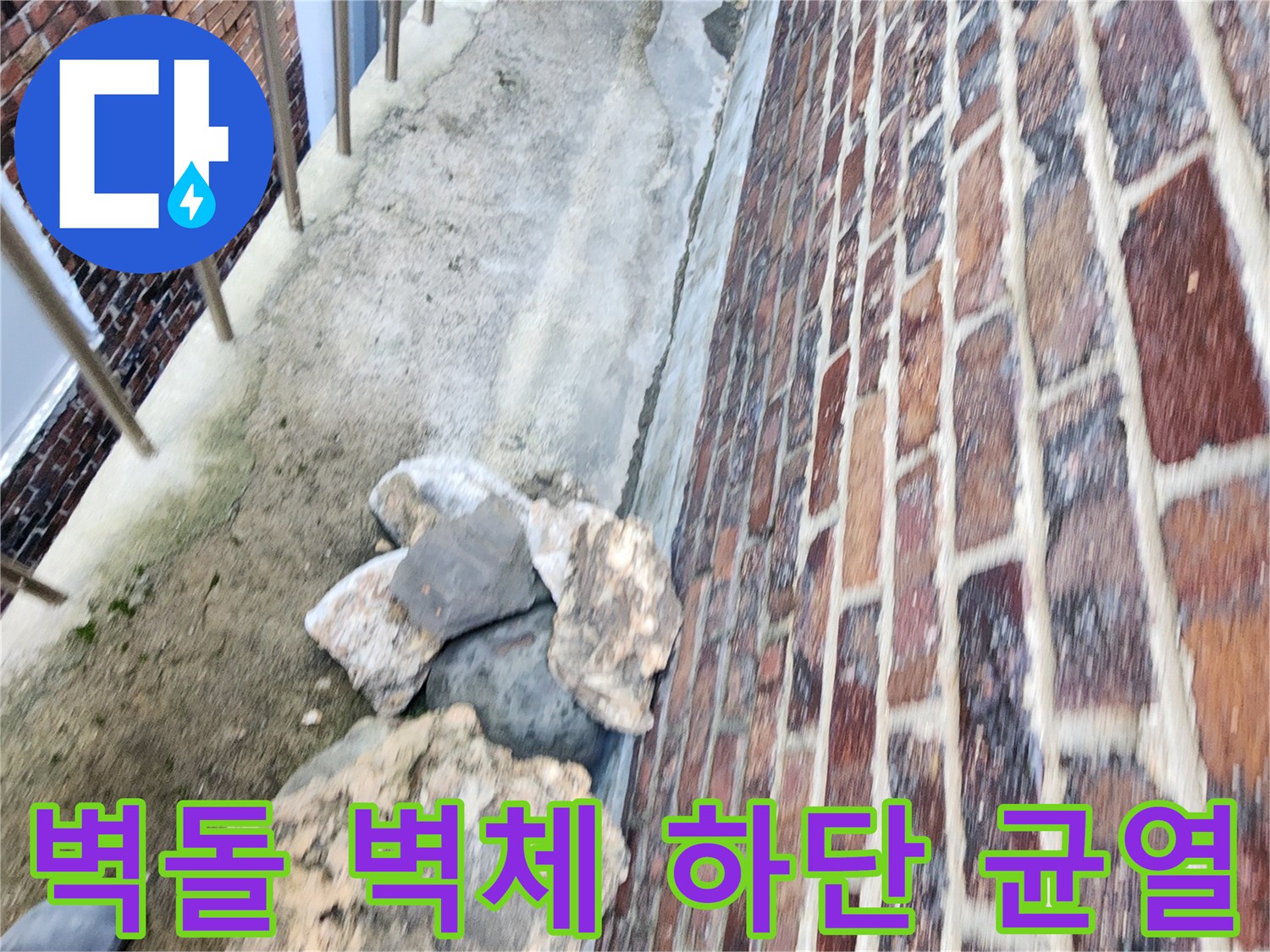 붉은 벽돌 외벽과 바닥 지면 사이의 갈라진 틈새를 촬영한 사진