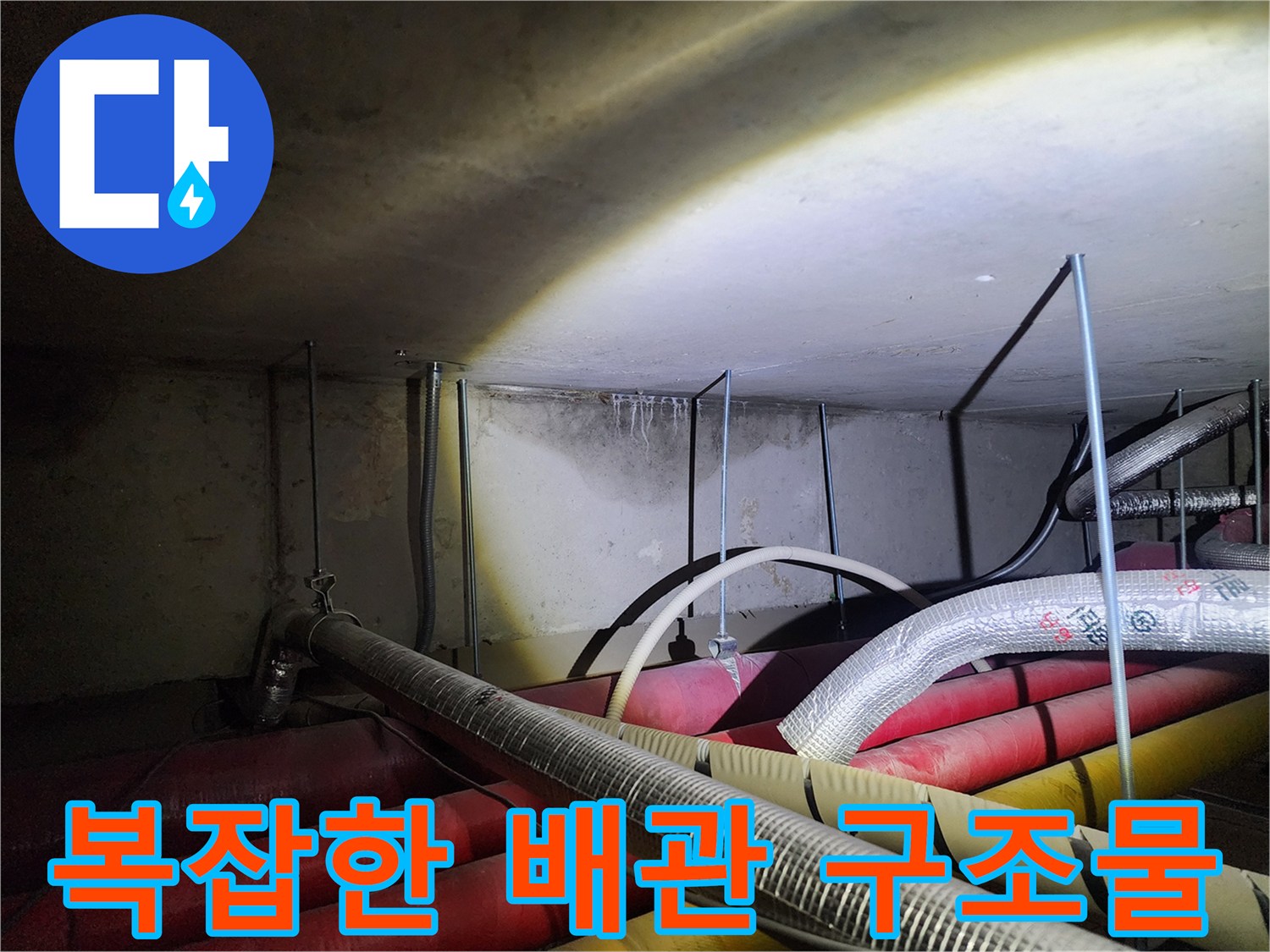 보온재로 감싸진-다양한 규격의 배관들이 밀집된 하부 공간 사진