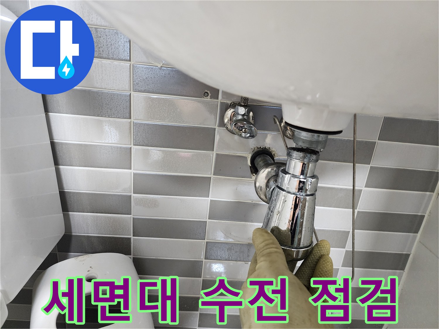 세면대 하단 배관의 누수 부위를 직접 만져보며 확인 중입니다.