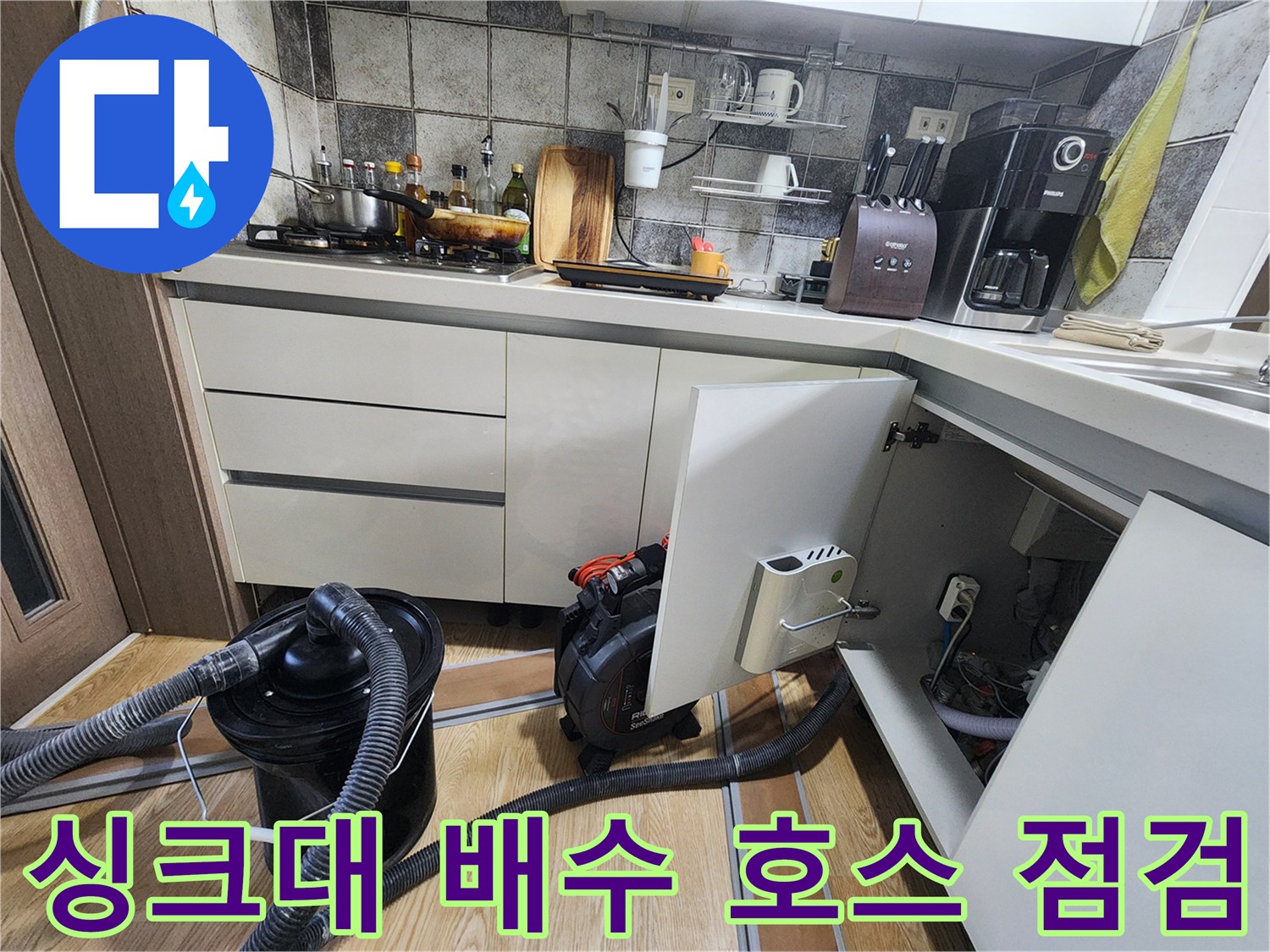 싱크대 하단 배수 호스와 청소 장비가 놓여 있는 현장 상황