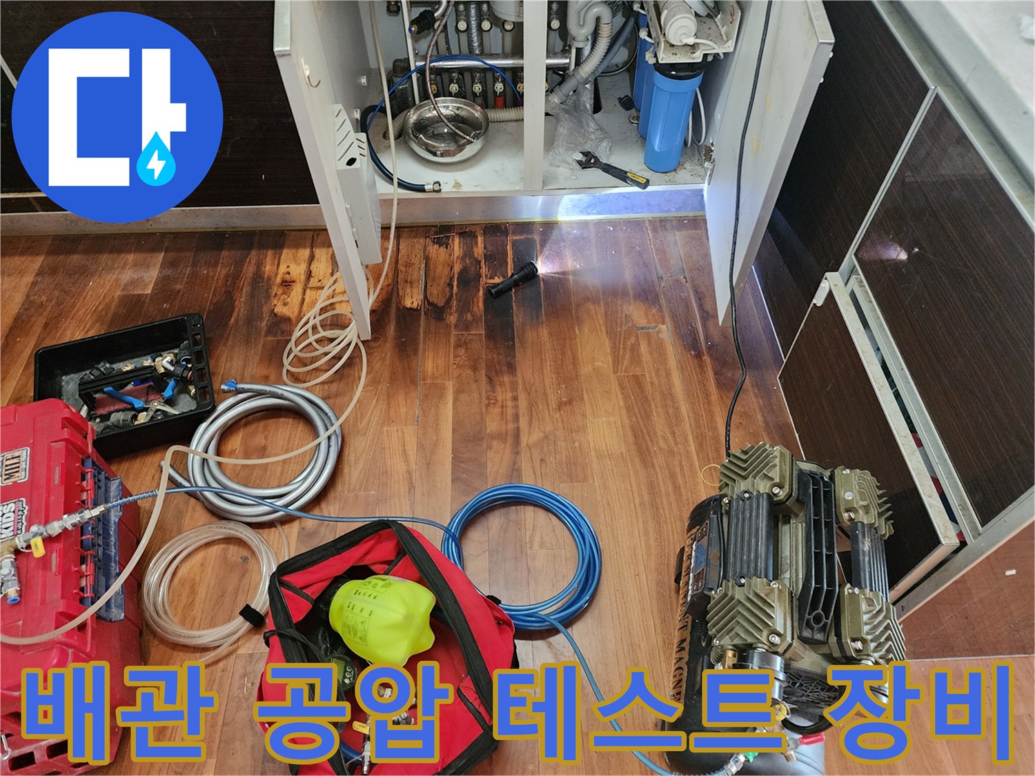 싱크대 하단 배관 점검을 위해 설치된 공압 테스트 장비와 호스