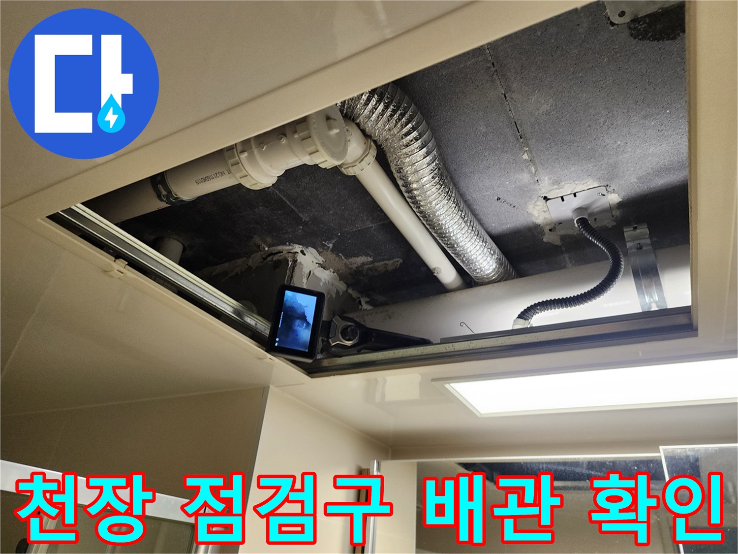 욕실 천장 점검구를 통해 내부 배수관과 환기 시설을 살펴보는 모습입니다.