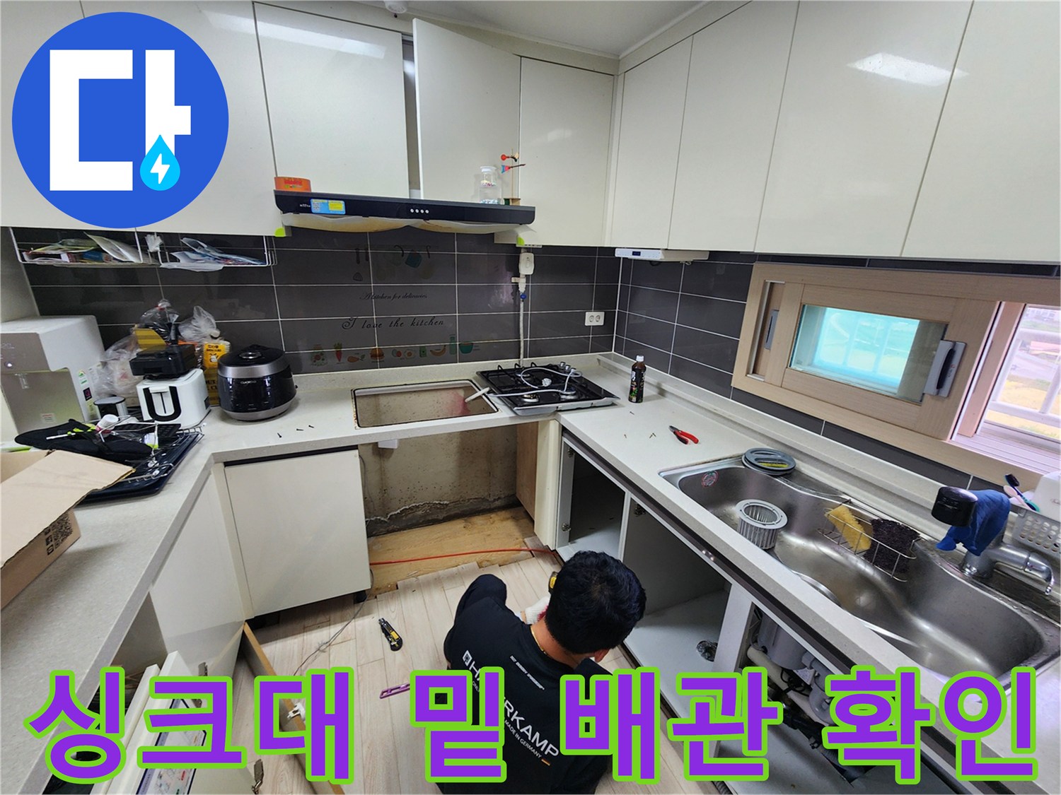 탈거된 싱크대 하부 공간에서 배관의 연결 상태를 점검하는 엔지니어