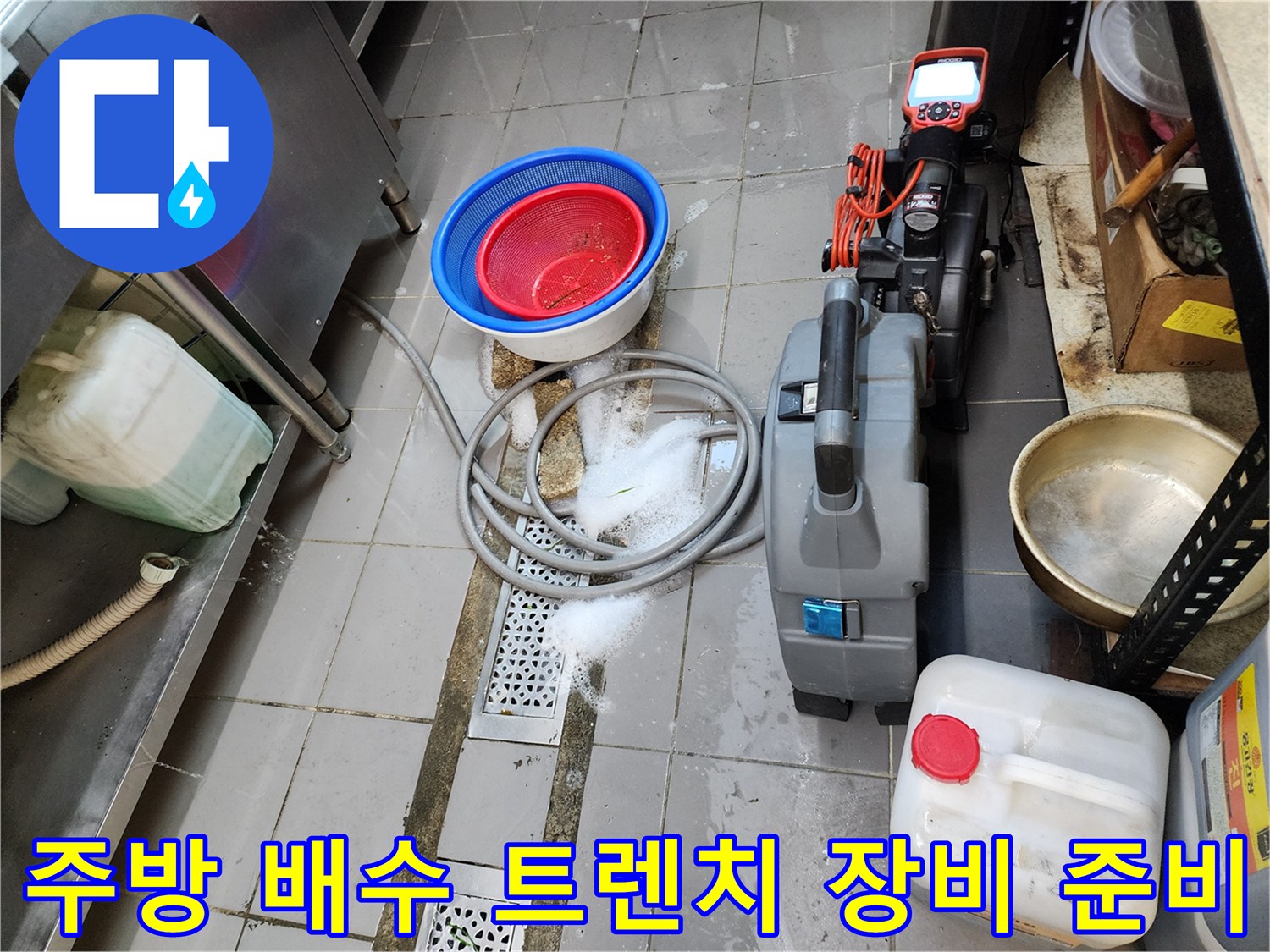 배수구 역류 해결을 위해 배치된 습식 청소기와 배관 작업 도구