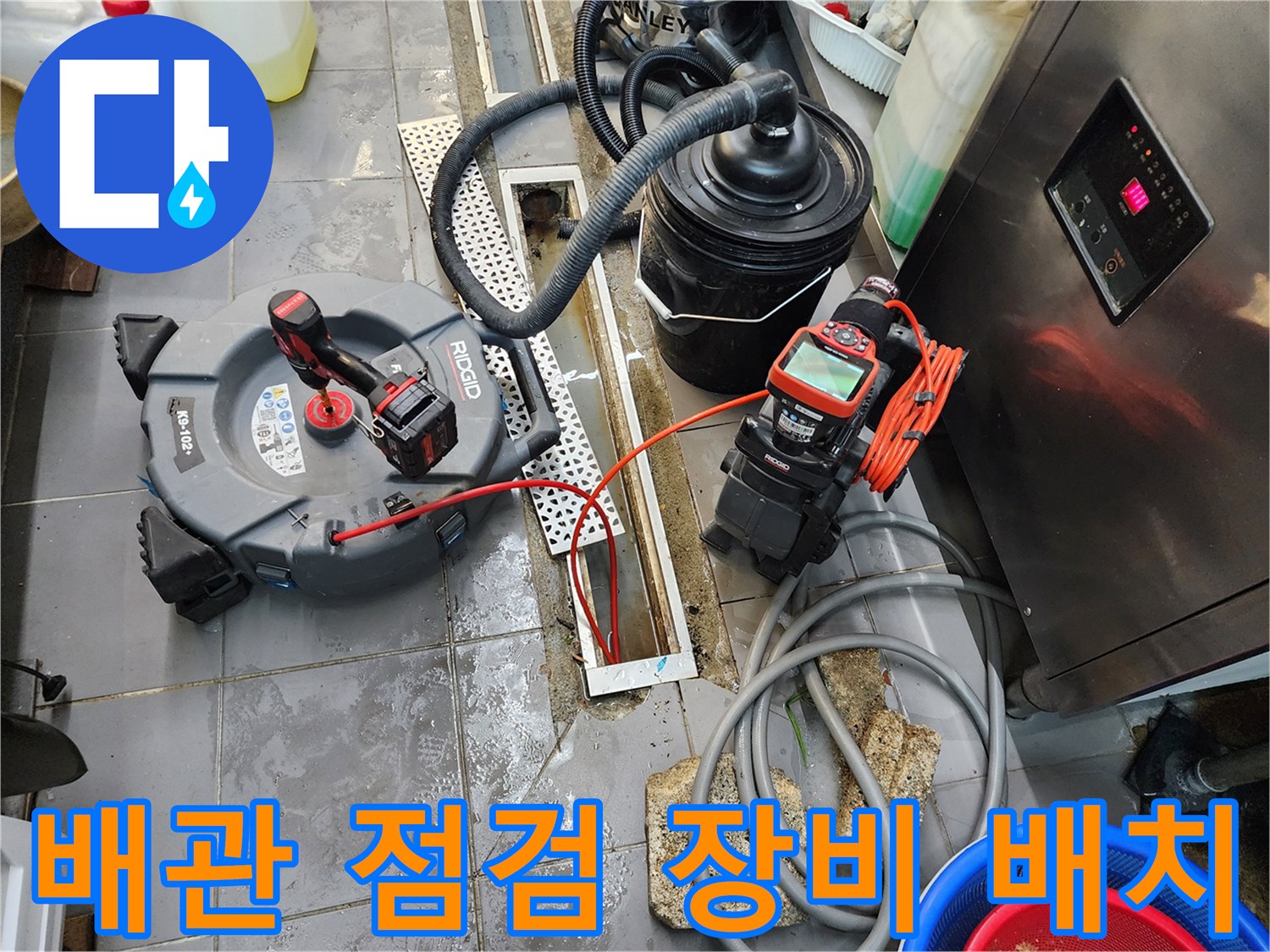 트렌치 배수구 옆에 내시경 카메라와 청소용 장비들이 놓여있는 장면입니다.