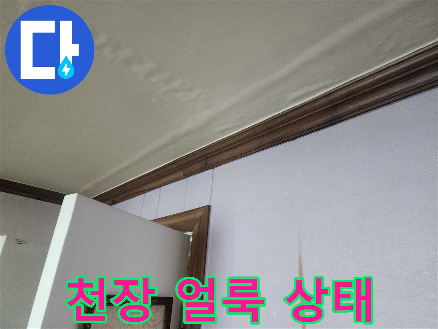 거실 천장 부근의 물샘 흔적과 벽지 변색 상태를 보여주는 사진입니다.