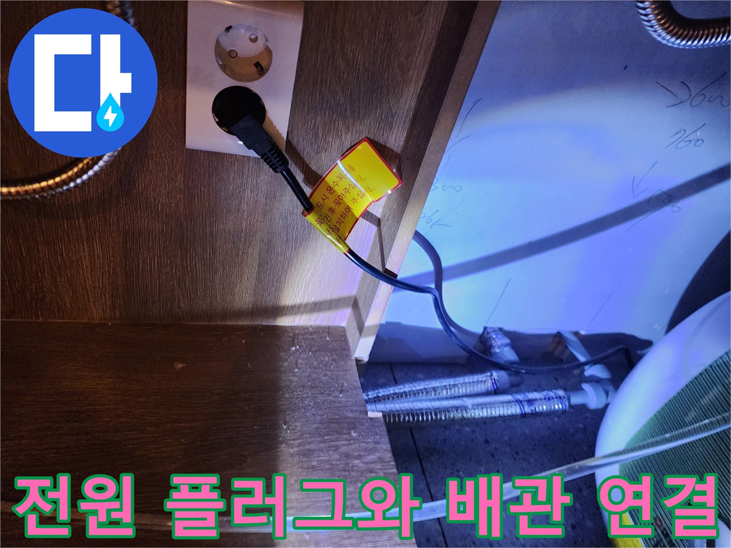 주방 싱크대 하부 콘센트 근처에 위치한 온수기 전선과 금속 호스