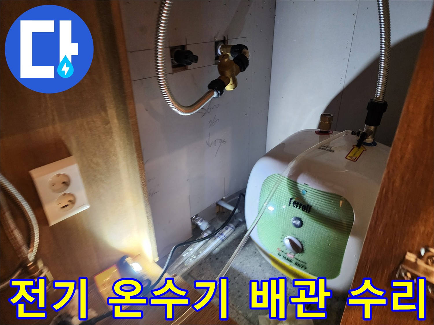 주방 싱크대 하부의 전기 온수기와 금속 연결 호스 사진