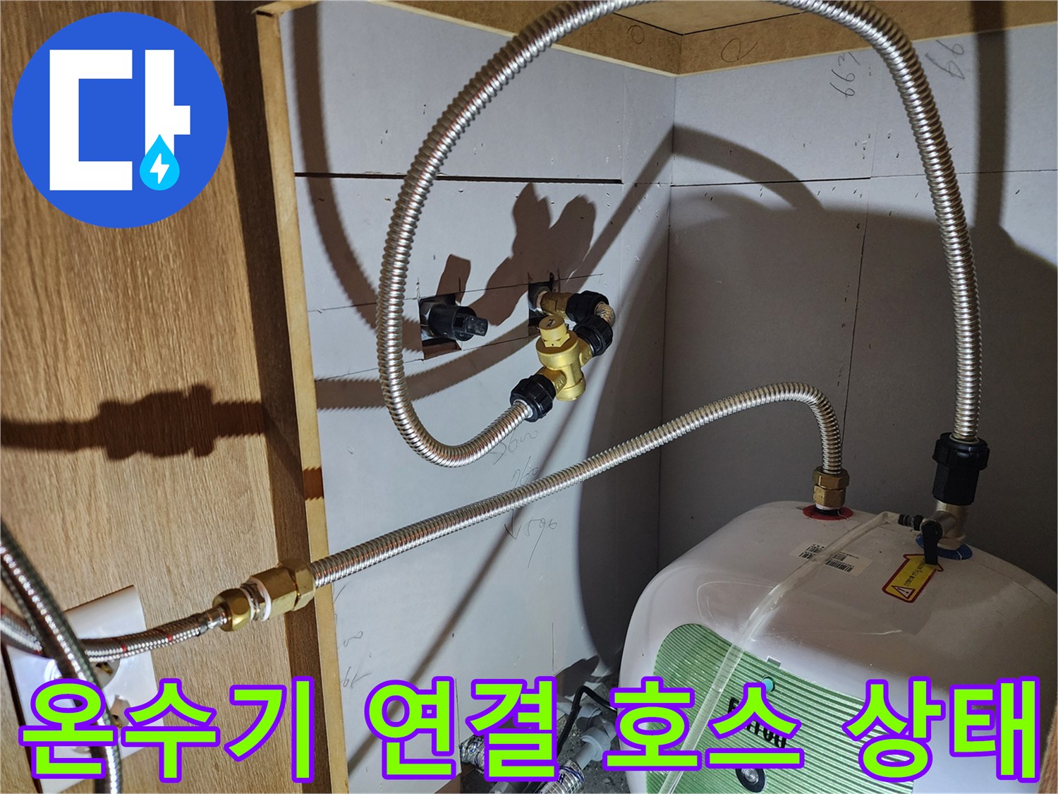 주방 하부장 내 전기 온수기와 배관 부속 연결 모습