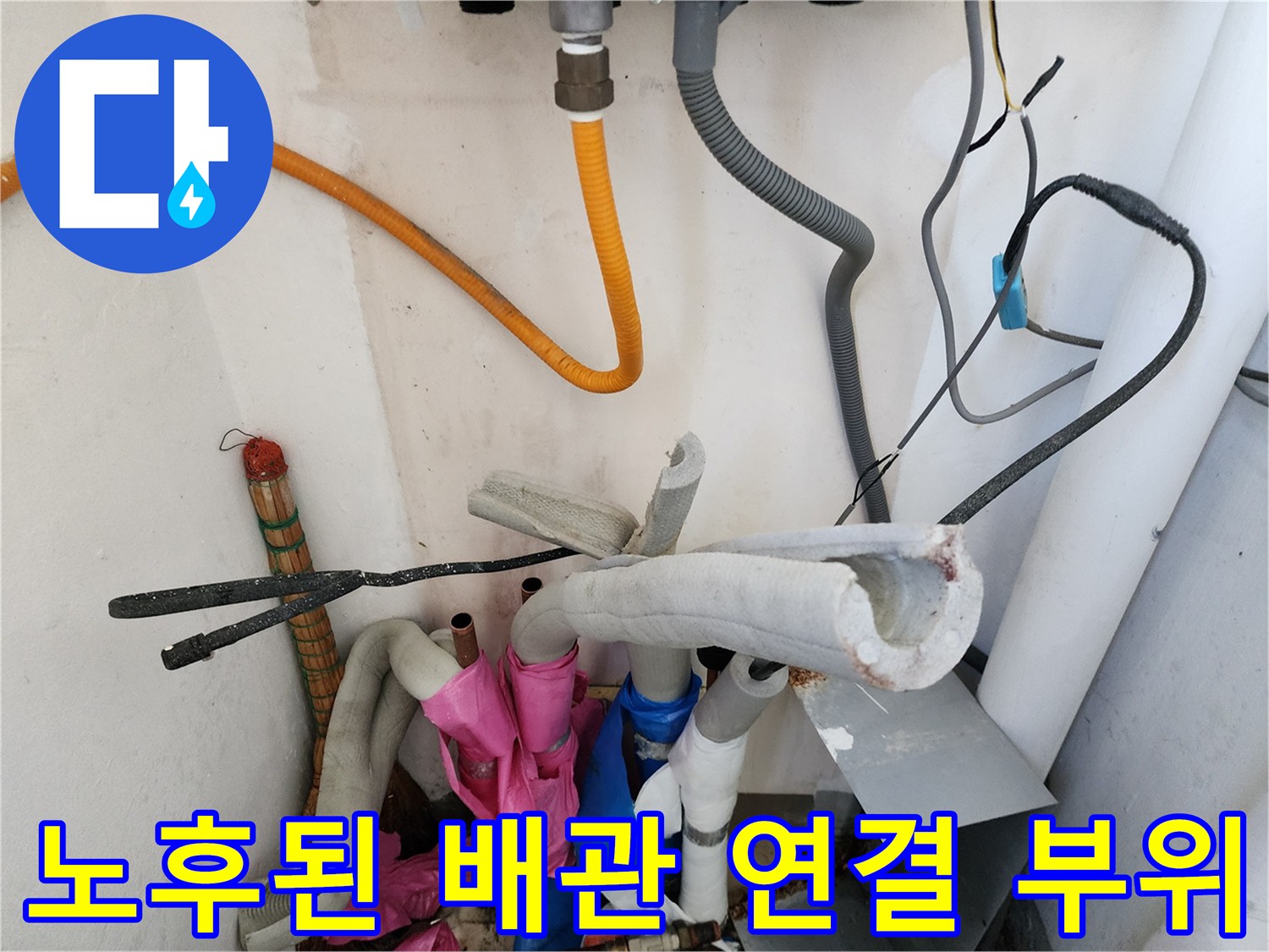 보온재가 벗겨진 배관과 노란색 유연한 관이 함께 보이는 보일러실 내부 전경