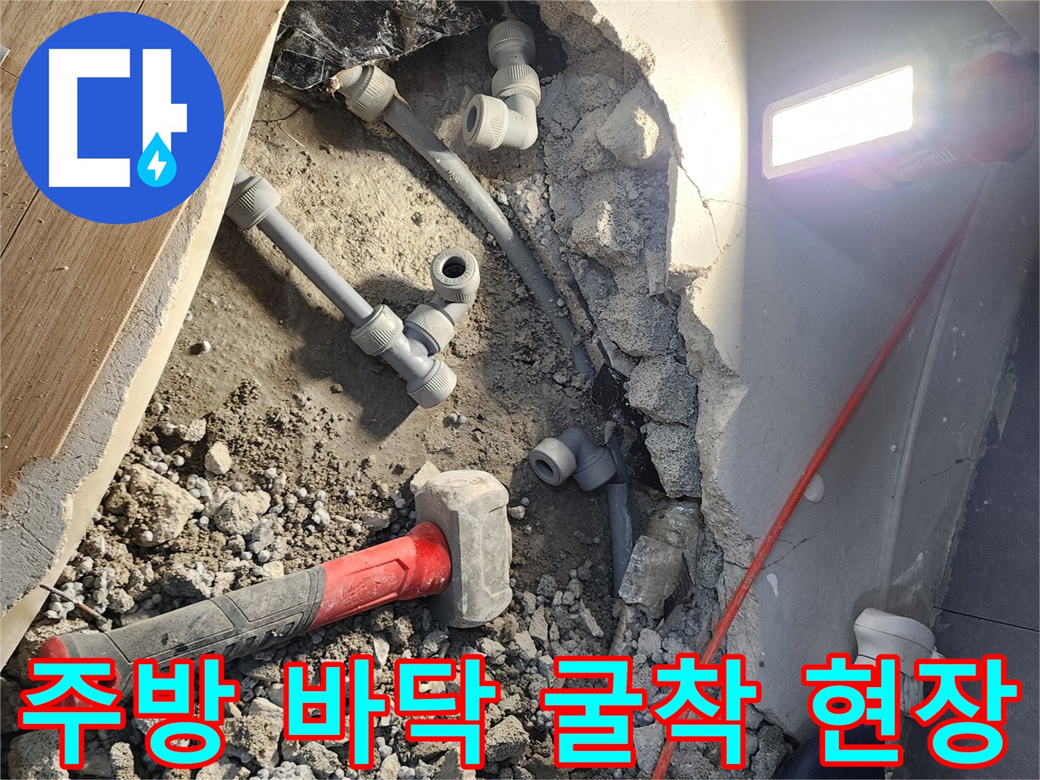 싱크대 하단 바닥 콘크리트를 제거하여 드러난 회색 배관과 공구들