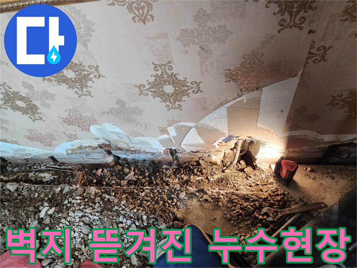 누수가 발생한 벽면 하단의 훼손된 벽지와 배관 노출