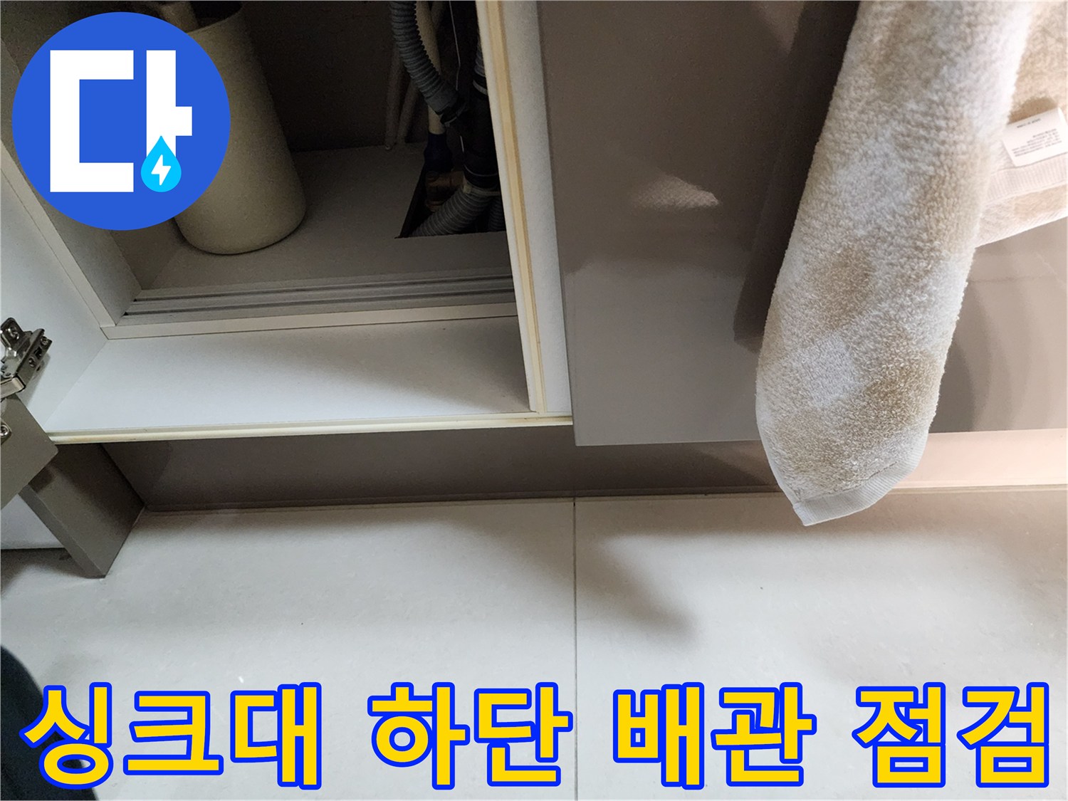 싱크대 하부장 내부의 배수 호스와 주변 바닥 상태를 촬영한 이미지