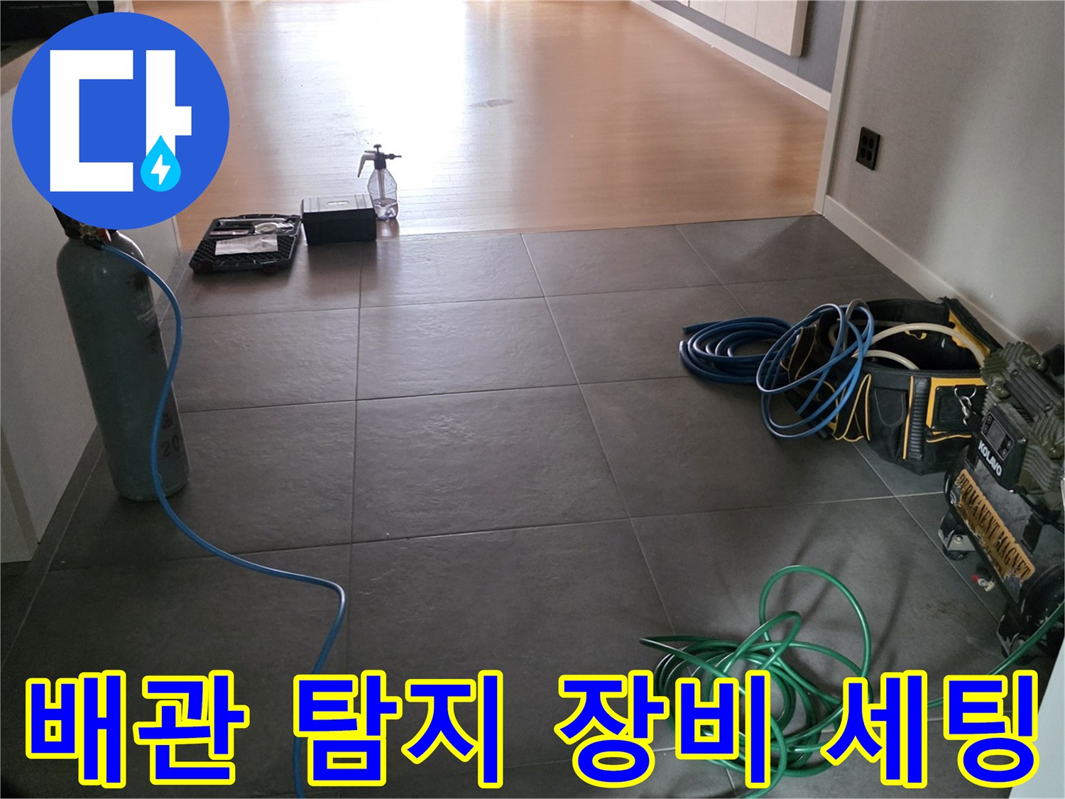 가스 주입용 용기와 탐지 호스가 거실 타일 바닥에 놓여 있는 작업 현장 사진