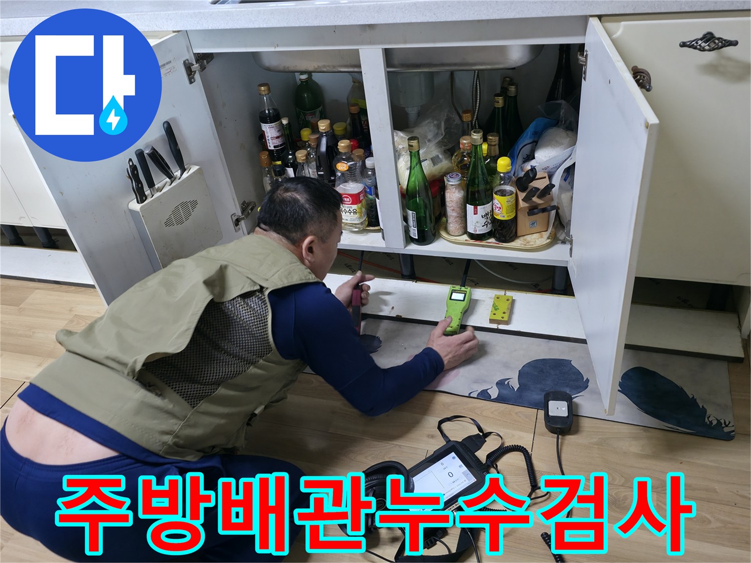 싱크대 하부 공간에서 가스 탐지기를 사용하여 배관의 결함을 찾는 모습입니다.