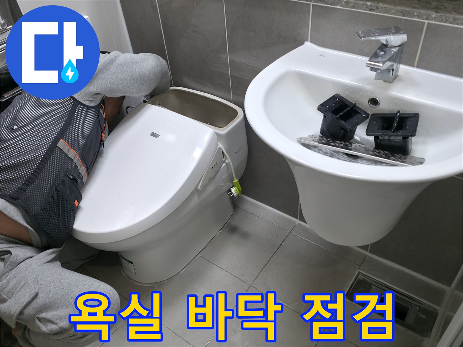 변기와 세면대 사이 타일 틈새의 습기 상태를 확인 중입니다