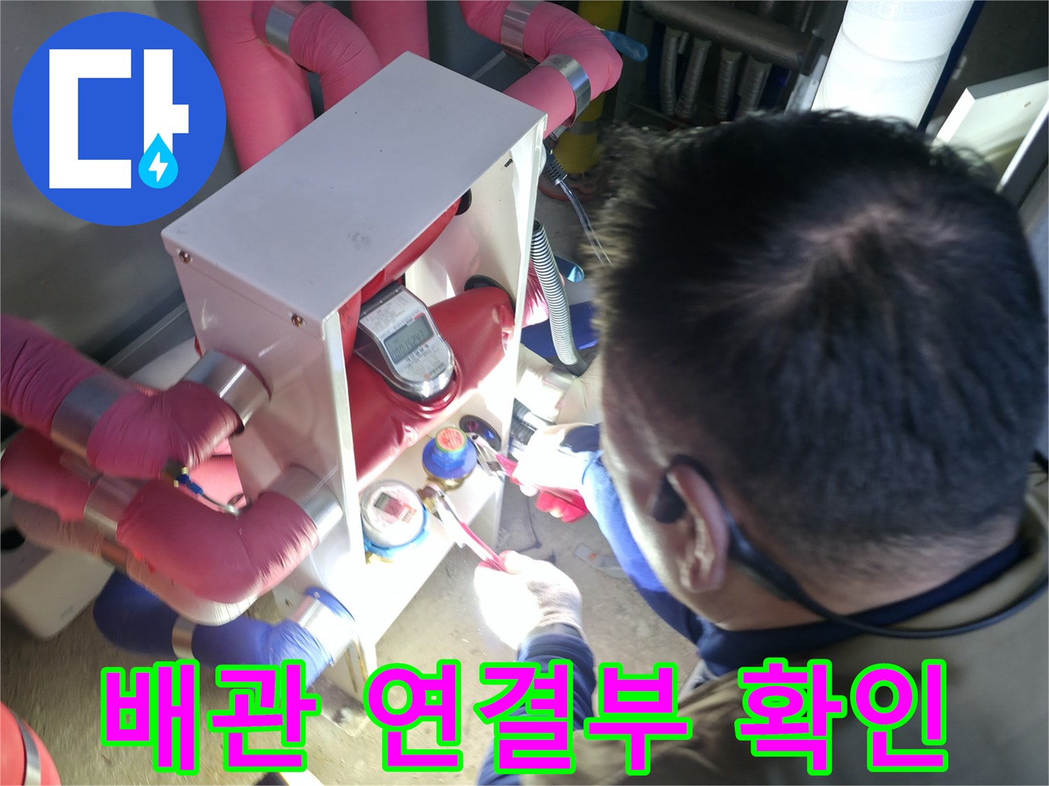 엔지니어가 분홍색 보온재가 씌워진 배관의 접합부를 정밀하게 검사합니다.