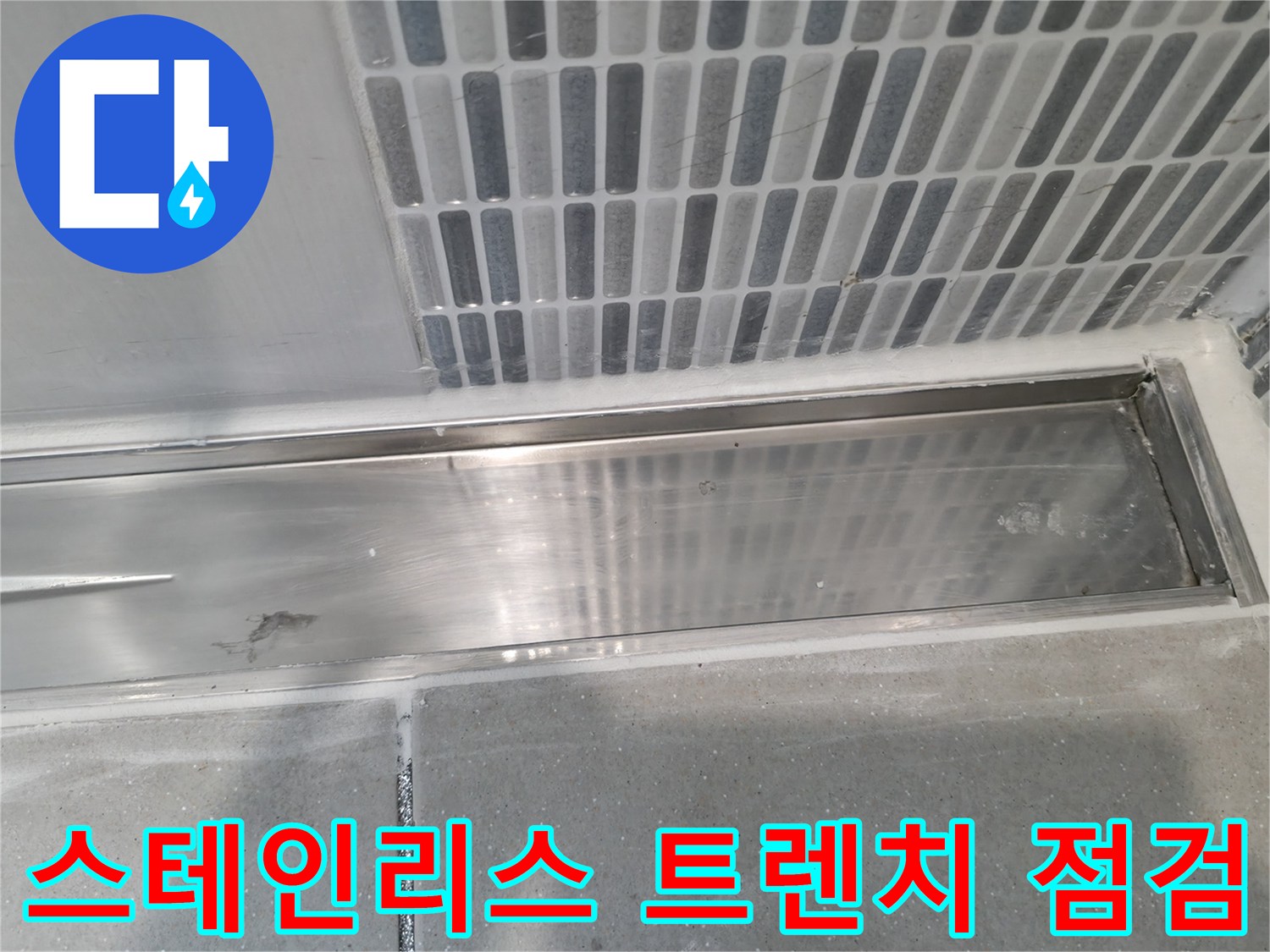 욕실 벽면의 세로형 타일과 스테인리스 배수 시설 접합부