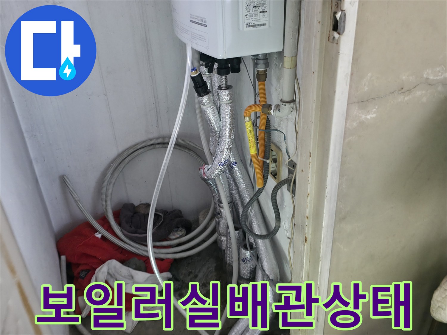 보일러 하단에 연결된 복잡한 배관과 보온재 상태를 보여주는 사진입니다.