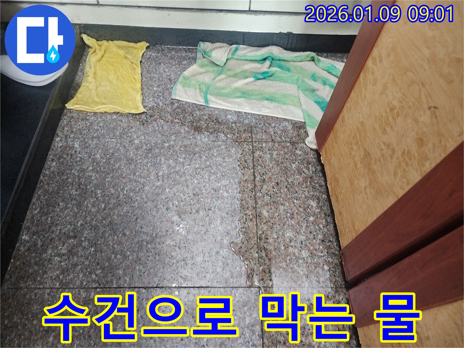 바닥에 물이 새어 나와 수건으로 막아 놓은 아파트 누수 현장-전문가가 완벽하게 보수해 드립니다.