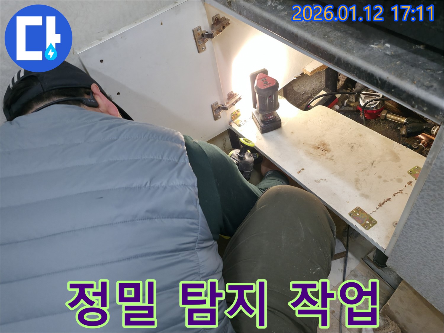 송파구 가락동 누수 현장에서 - 누수 전문가가 전문 장비를 사용하여 싱크대 하부 누수 지점을 정확하게 탐지하는 모습입니다.