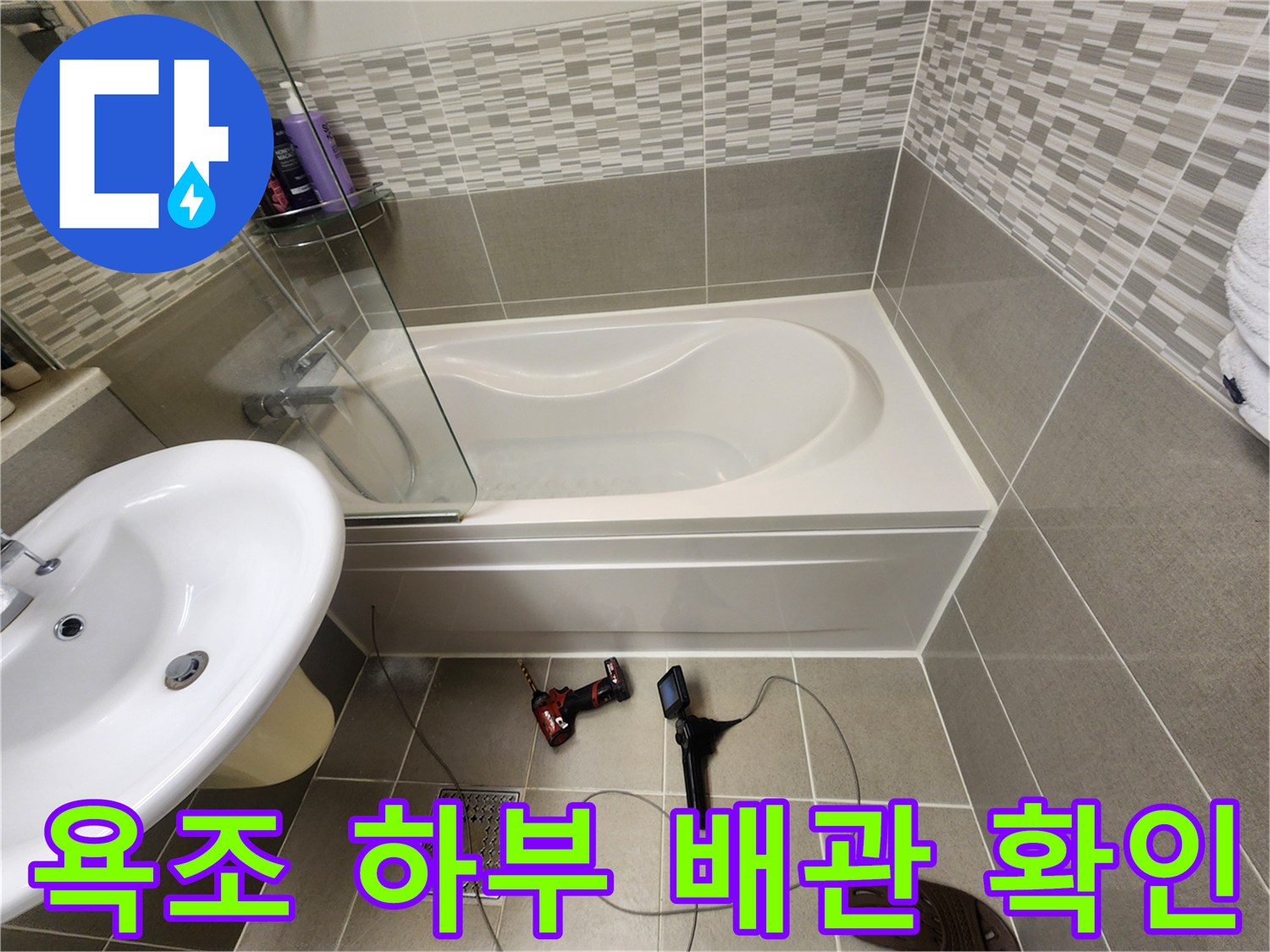 욕조 측면을 열고 내시경 장비로 내부 배관을 검사하는 모습