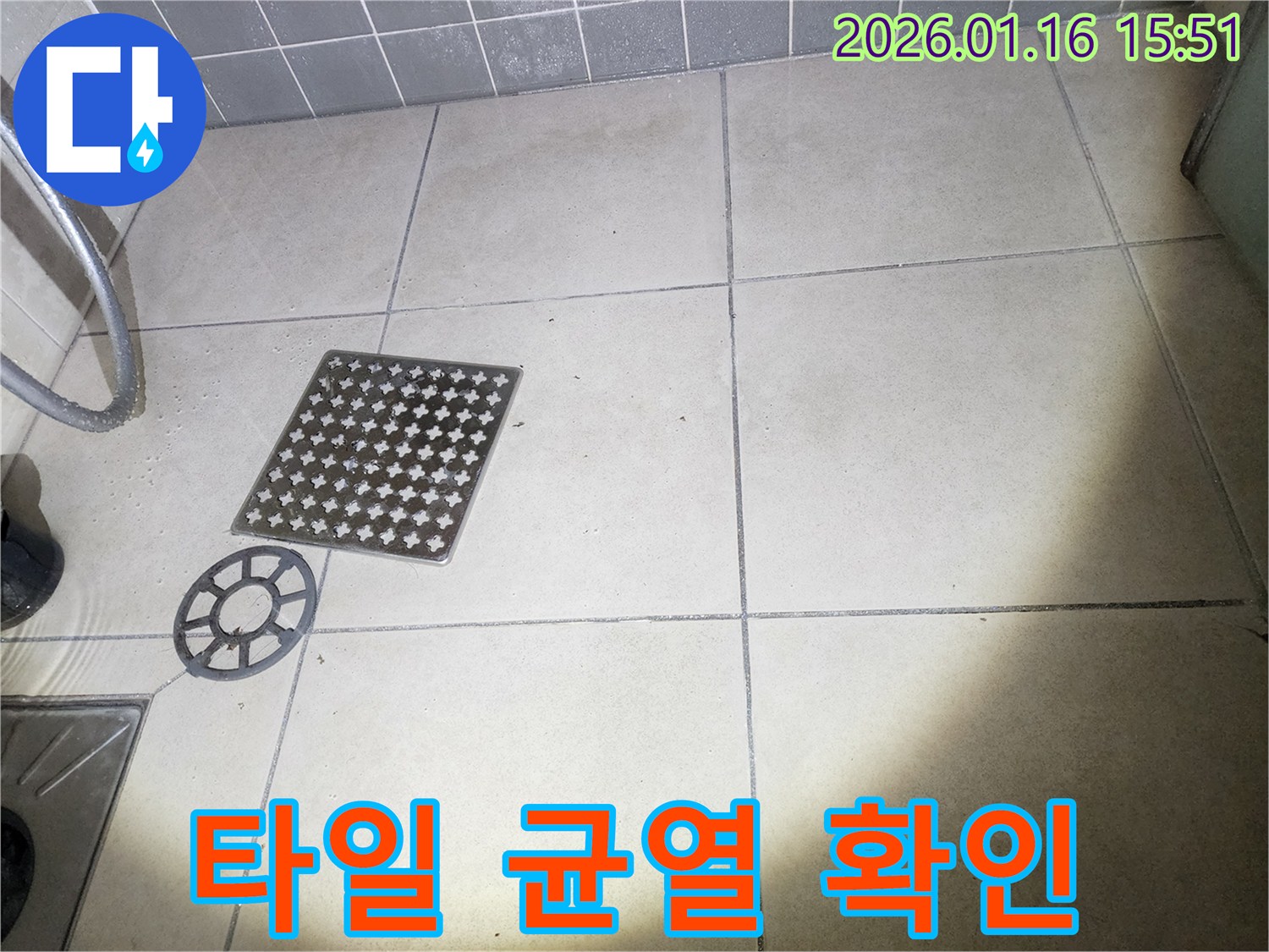 이 이미지는-욕실 배수구 커버를-제거한 후-주변 타일의-미세한 균열을-확인하는-장면을 보여줍니다