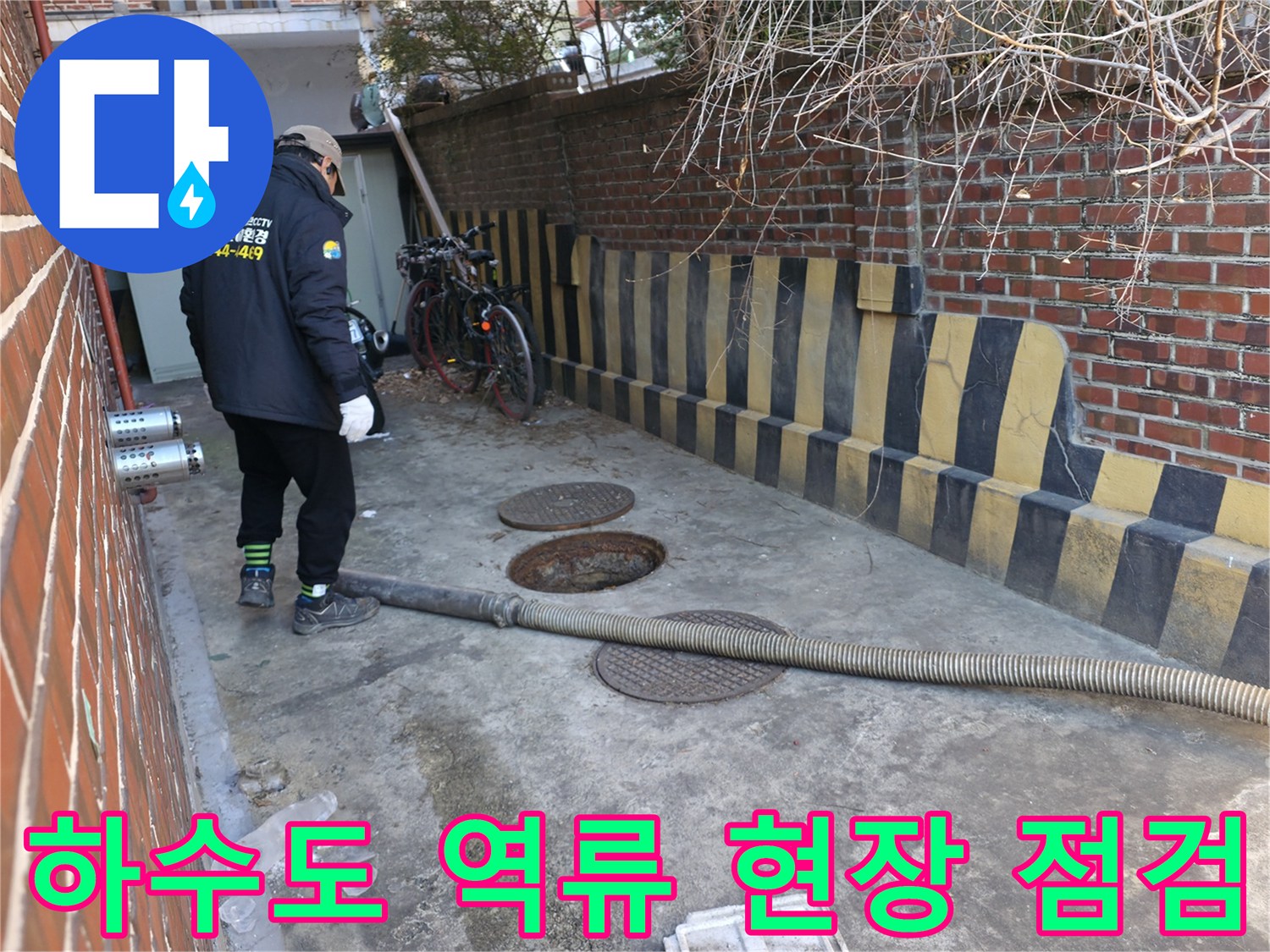 맨홀 덮개와-흡입 호스가 놓여 있는 외부 작업 현장