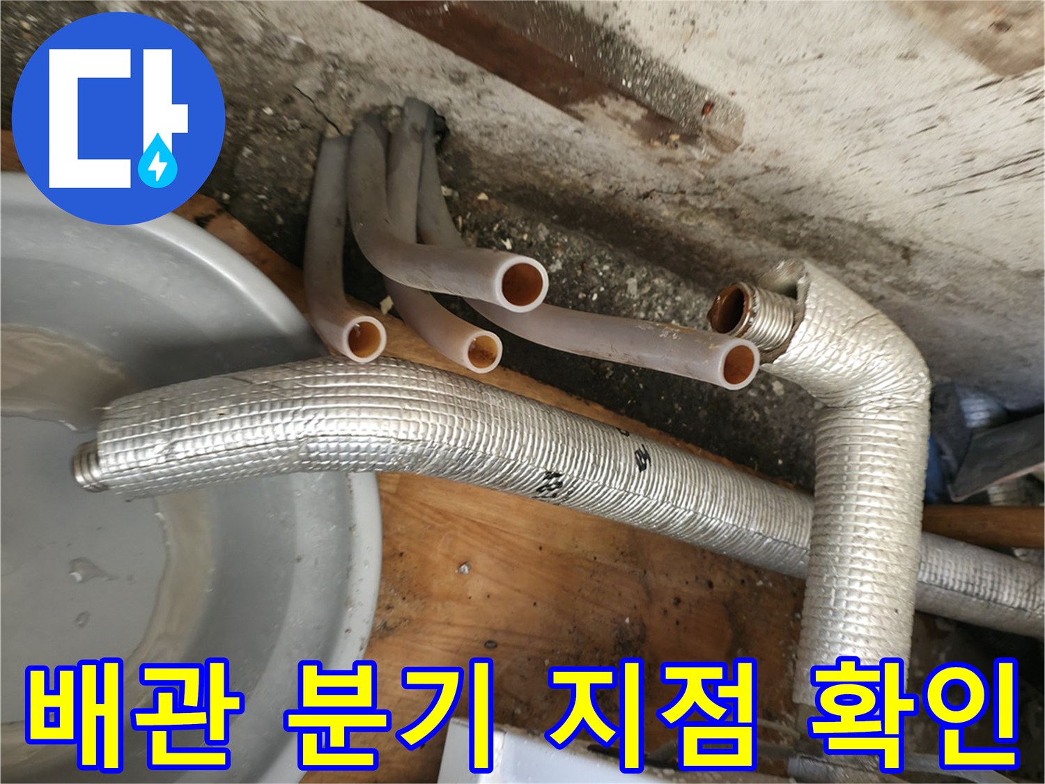 보온재가 씌워진 배관과 노출된 주황색 배관이 만나는 하단부 모습입니다.